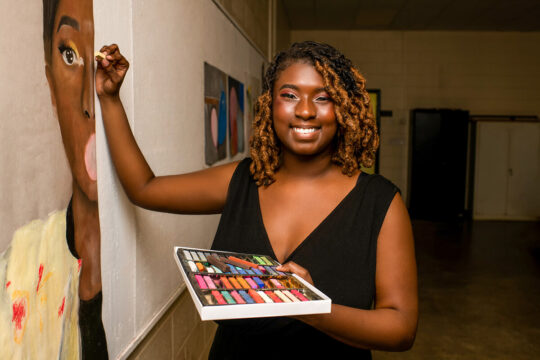 SSU Studio Art Student posing with a painting