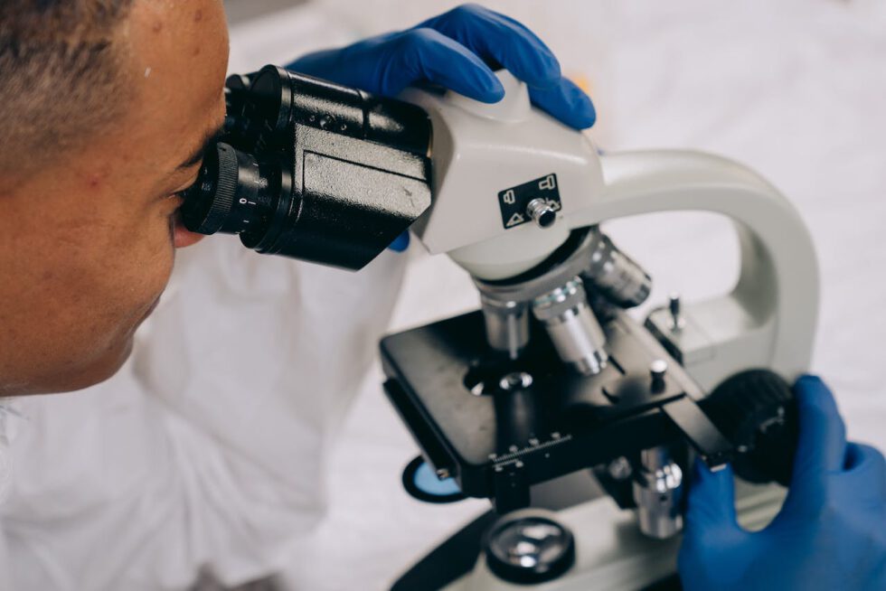 black man using a microscope science biology