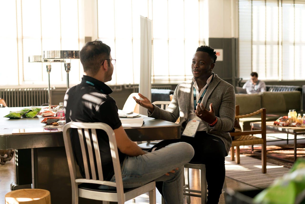 black man with lanyard speaking to student in library