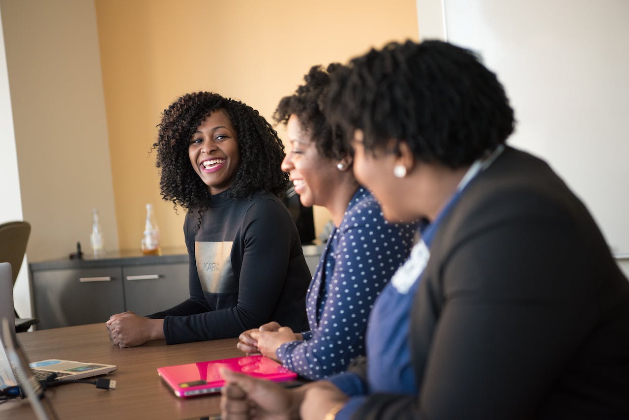 black women at conference table smiling