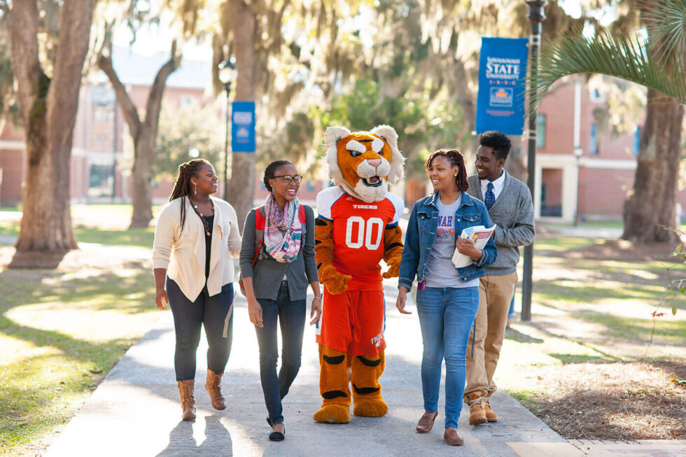 four students walking with mascot smiling sunshine