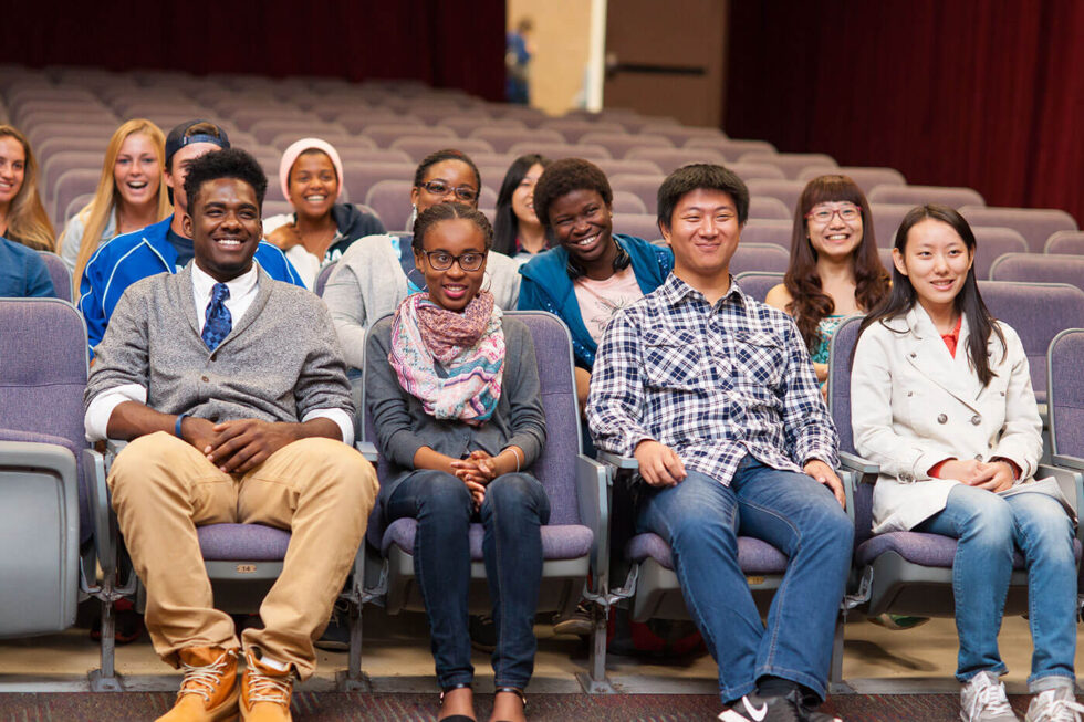 international students together in auditorium studying smiling
